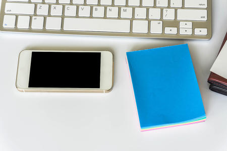 Office desk top view with smartphones, laptop eyeglasses and book / Office supplies Blank and pen notebook and earphones on white backgroundの写真素材
