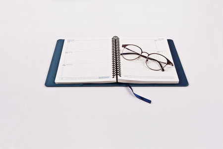 Notebook and glasses on a white background. View from above.