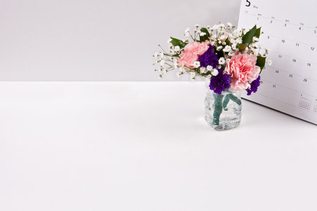 Flower bouquet in glass vase and calendar on white backgroundの写真素材