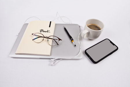 Notebook with pen, glasses and a cup of coffee on a white backgroundの写真素材