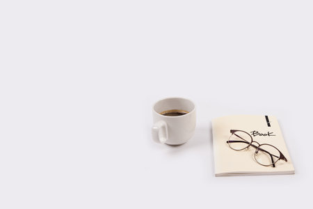 Cup of coffee with notebook and glasses on white backgroundの写真素材