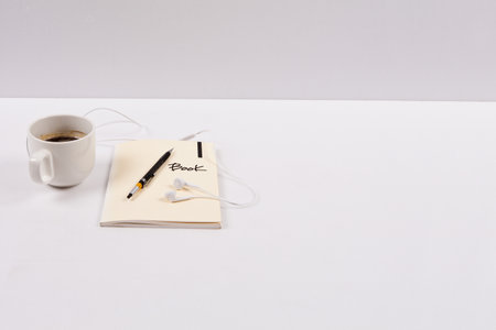 A cup of coffee and a note with a pen on a white background