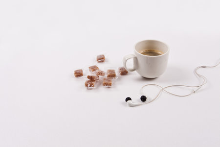 Coffee cup with headphones and sugar cubes on a white backgroundの写真素材