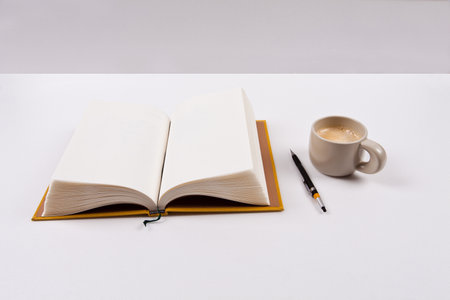 Open book, pen and cup of coffee on a white background.の写真素材