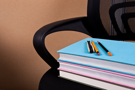 Stack of books and pencils on office chair. Back to school concept.の写真素材