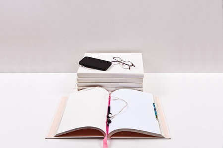 Notebook with smart phone and glasses on the table. White backgroundの写真素材