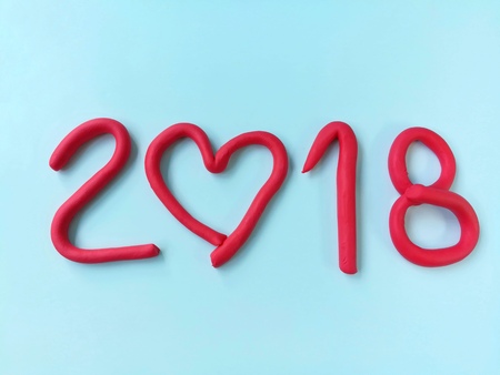 Red numbers yearÂ 2018,made of colorful clay plasticine,beautiful a number 0 creates a heart shape on a blue backgroundの写真素材