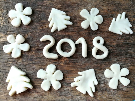 Beautiful wallpaper with number year 2018 ,Christmas tree and white flowers are made from clay plasticine placed on dark wooden background,festival doughの写真素材