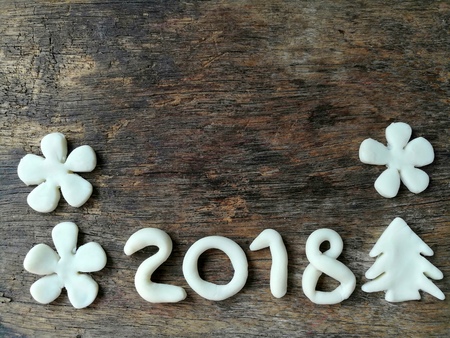 Beautiful wallpaper with number year 2018 ,Christmas tree and white flowers are made from clay plasticine placed on dark wooden background,festival doughの写真素材