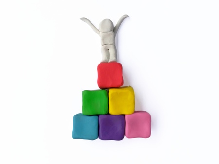 The winner stand up and raised his hands on  colorful pyramid blocks  on white background, person doughの写真素材