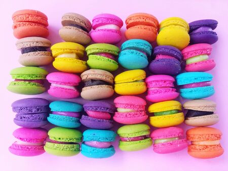 Delicious macaron sweets arranged in rows, colorful macaroon on pink backgroundの写真素材