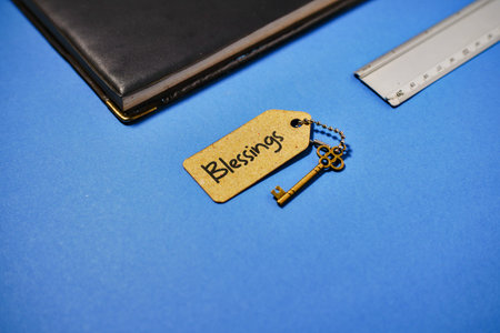 A symbolic image representing blessings, featuring a key attached to a tag with the word Blessings, placed near a notebook and a ruler.