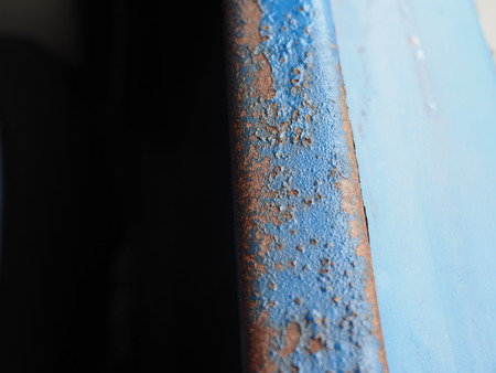 Old dirty rusty torn teared blue painted iron bar window border of Thai public bus, with dark black half left, and blurred blue area on the rightの写真素材