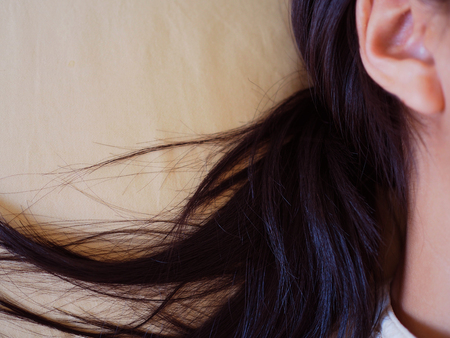 Close up Asian shiny messy black woman hair spread on crease yellow cloth pillow backgroundの写真素材