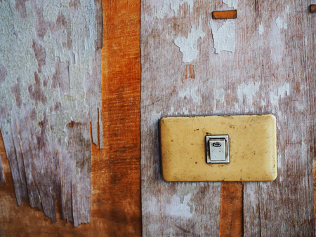 Old yellow plastic lighting switch panel attached on weathered damaged stained peeled off dirty...