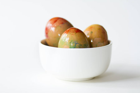 Freshly painted, colourful, Easter eggs sit in a white porcelain bowl 