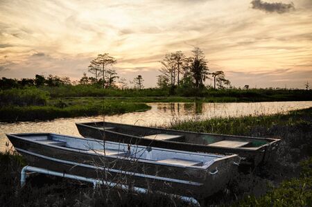 Silhouettes of tin boats sit on the shore of the Everglades in South Floridaeの写真素材