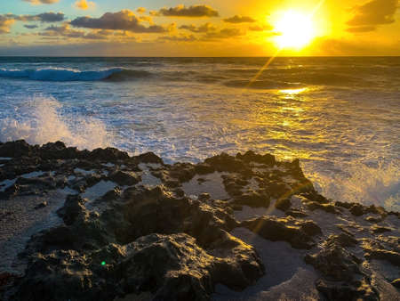 Ocean foam shining in sunrise creates a rainbowの写真素材