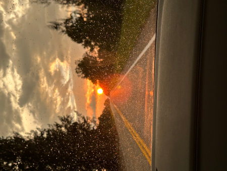 Sunset on the road through the windshield of a car in the rainの写真素材