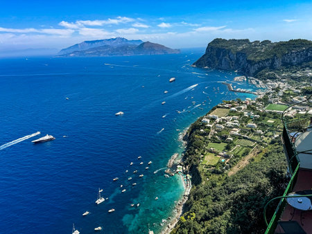 Panoramic aerial view of the dramatic cliffs of Capri overlooking the deep blue waters of the Bay of...