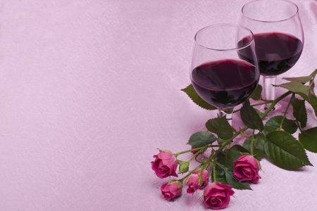 two glass with wine and roses on a pink  backgroundの写真素材
