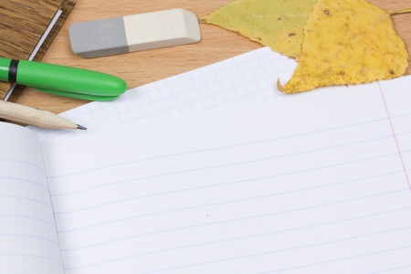 Opened school notebook and pencil, pen, eraser, leaves