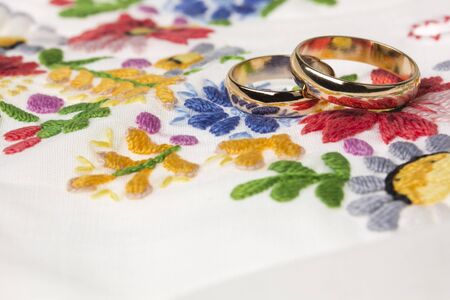 Wedding rings on a background of embroidered flowersの写真素材