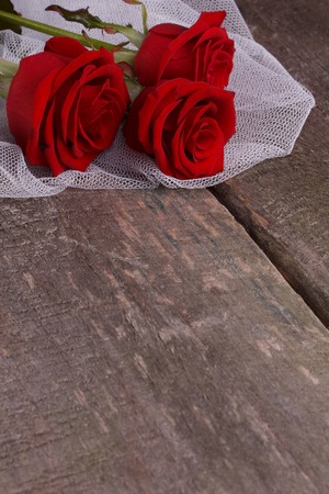 Three red roses on a wooden backgroundの写真素材