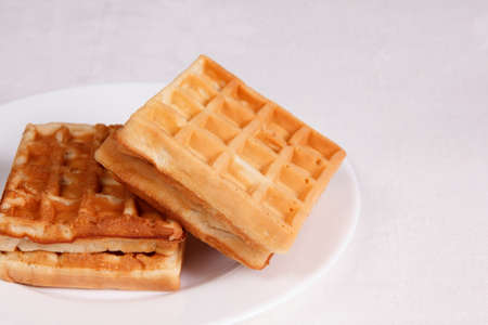 Sweet waffles in a white plate on a tableclothの写真素材