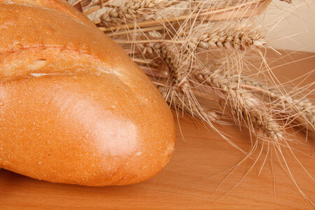 Fresh bread and wheat ears on the kitchen tableの写真素材