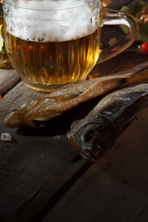 Mug of beer and dried fish on old wooden boardの写真素材