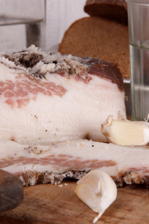 Sliced lard on a wooden desk with onion,  vodka and breadの写真素材