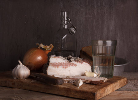 Sliced lard on a wooden desk with onion,  vodka and breadの写真素材
