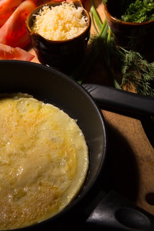 Scrambled eggs with cheese and fresh herbs on the tableの写真素材