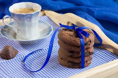 Fresh cookies and a cup of coffee on a wooden trayの写真素材