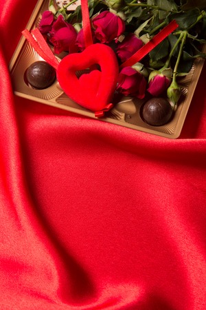 Chocolate candies and rose on a red backgroundの写真素材