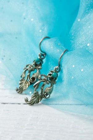 A pair of earrings with blue stones on on blue clothの写真素材