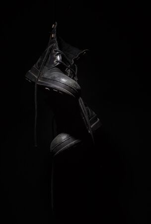 old shoes hanging on a black backgroundの写真素材
