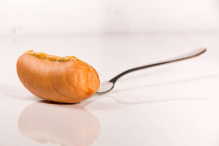 Fresh sausage with mustard on metal forkの写真素材