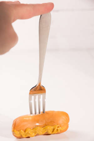 Fresh sausage with mustard on metal forkの写真素材