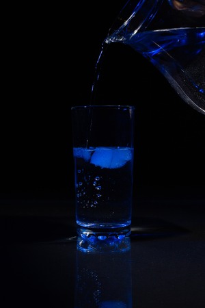 Glass of water with ice on a dark background