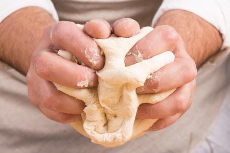 Baker holds raw dough for bread in handsの写真素材