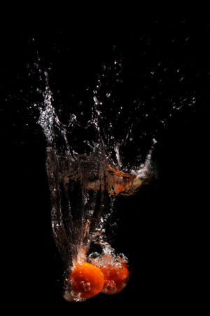 Two mandarins fall into the water on a black backgroundの写真素材