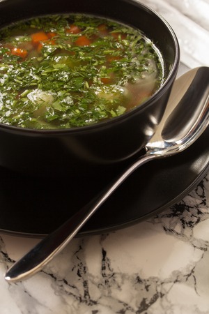 Vegetable soup in a black plate, on a dark backgroundの写真素材