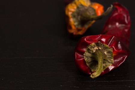 Two hot red dry peppers on a black backgroundの写真素材