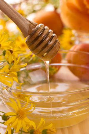 Honey stick and glass jar with honeyの写真素材
