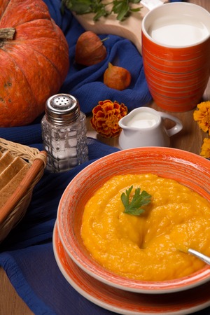 Pumpkin cream soup in a ceramic plate on the kitchen tableの写真素材