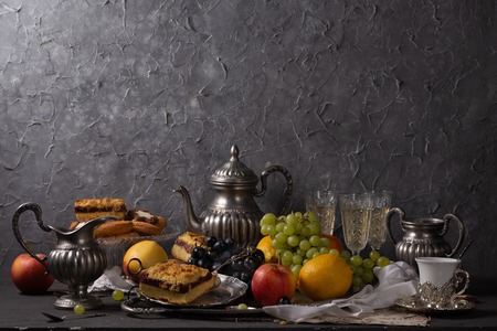 Still life with vintage silver items, fruits and sweetsの写真素材