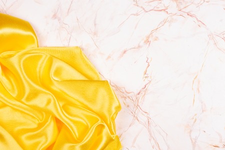 Brilliant yellow silk fabric on marble and place for text.の写真素材