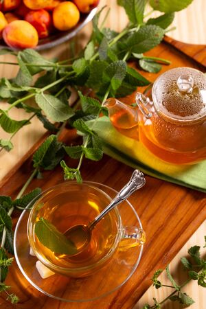 Fresh hot tea and mint on a wooden trayの写真素材